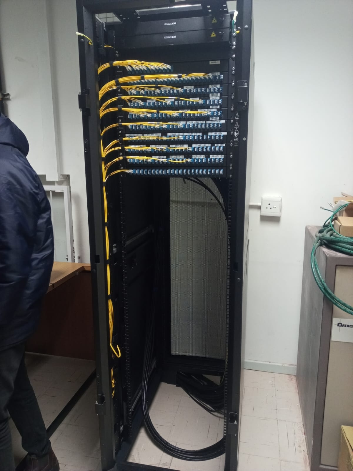 Multiple rows of optical connections with yellow patch leads routed down the side of the rack.