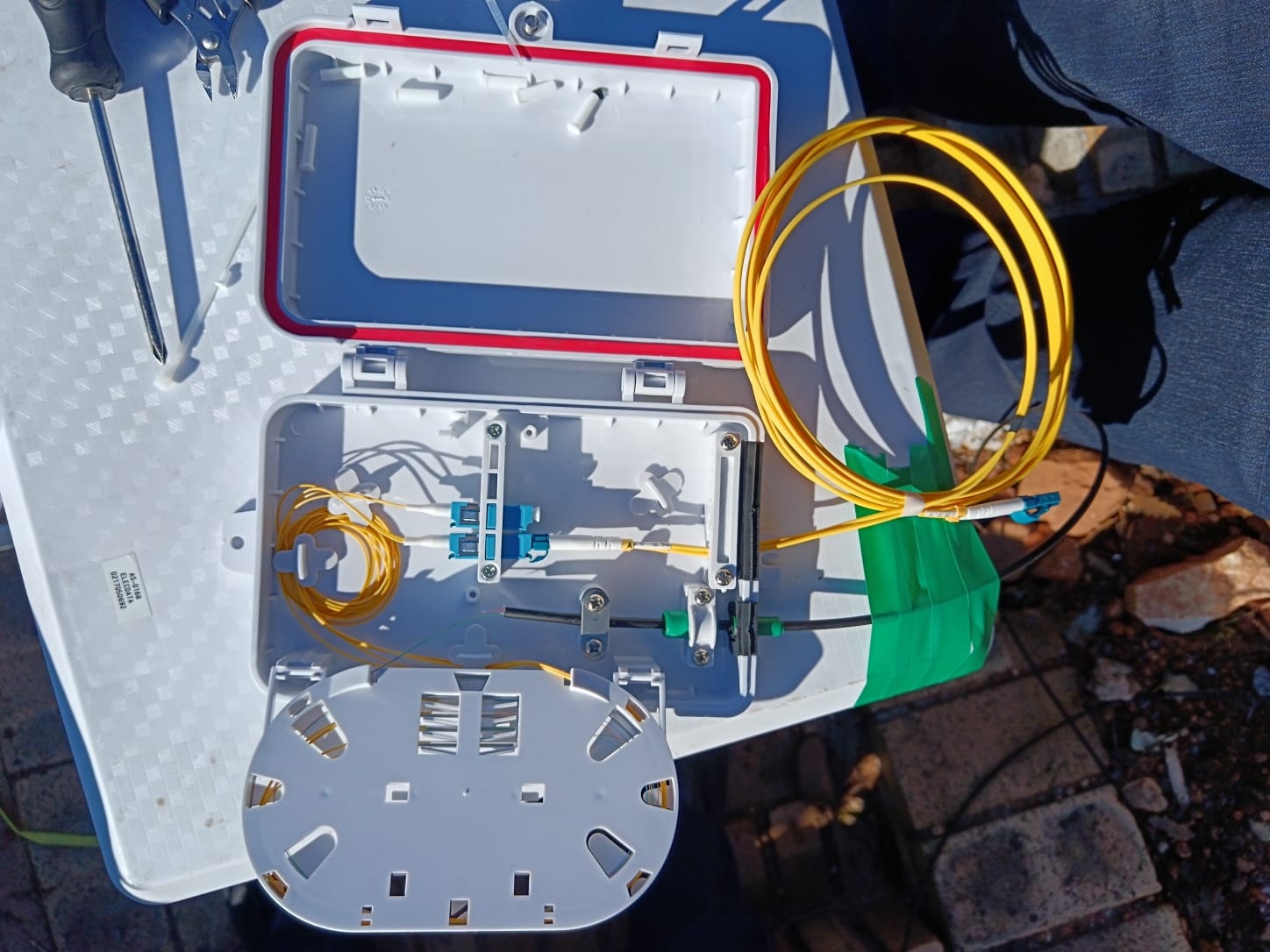 An open fibre enclosure showing optical adapters, a splice tray and routed yellow fibre.